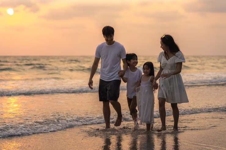 Family walking together on the beach at sunset